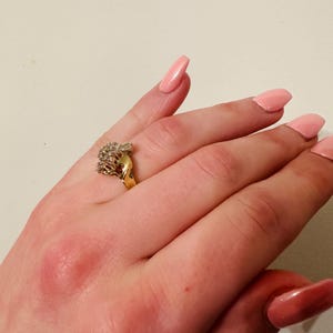 May include: A gold ring with a cluster of clear stones set in a heart shape.