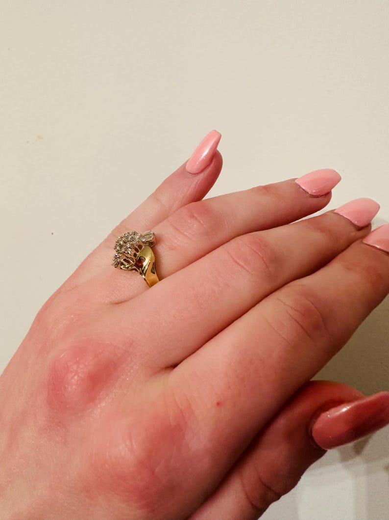 May include: A gold ring with a cluster of clear stones set in a heart shape.