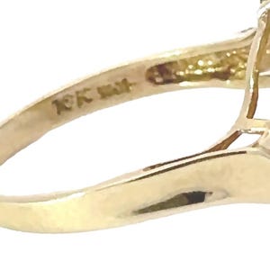 May include: Close-up of the inside of a gold ring with the inscription "10K 14K" on the band.