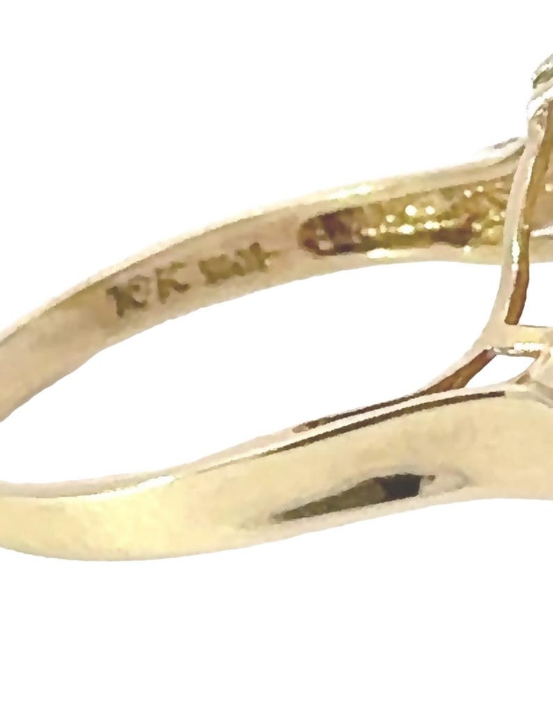 May include: Close-up of the inside of a gold ring with the inscription "10K 14K" on the band.