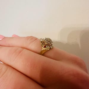 May include: A gold ring with a large cluster of clear stones set in a flower-like design.