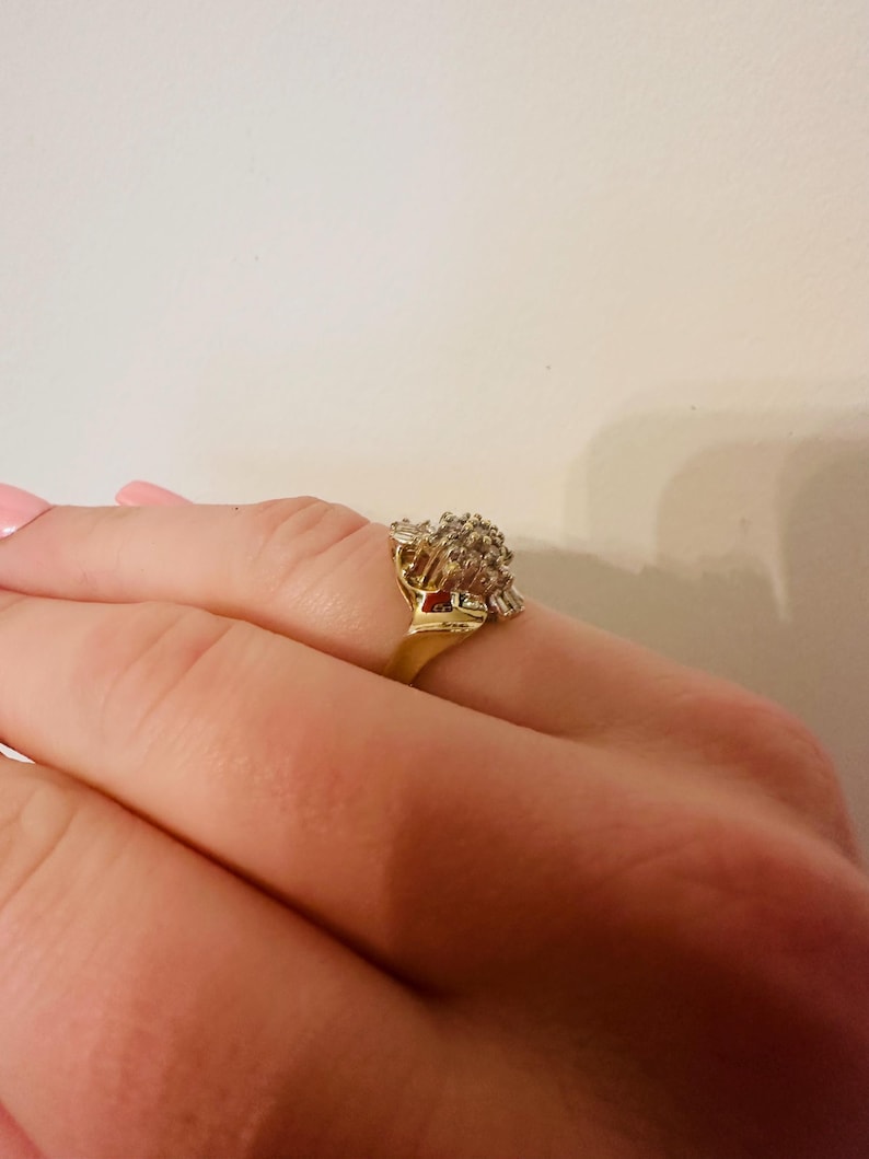 May include: A gold ring with a large cluster of clear stones set in a flower-like design.