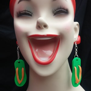 May include: A mannequin wearing a red headband and green and orange flip-flop earrings.