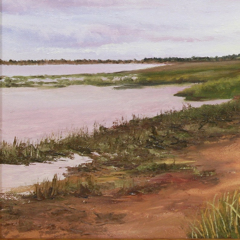 May include: An oil painting of a tranquil landscape. A body of water reflects a soft pink hue under a cloudy sky. The foreground shows a sandy bank and patches of green grass, creating a peaceful scene.