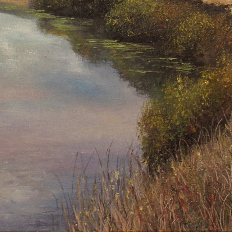 Puede incluir: Pintura al &oacute;leo de una escena de r&iacute;o tranquila. El agua refleja el cielo, con toques de azul y gris. El exuberante follaje verde bordea las orillas, con hierbas altas y secas en primer plano. La obra de arte evoca una sensaci&oacute;n de tranquilidad.