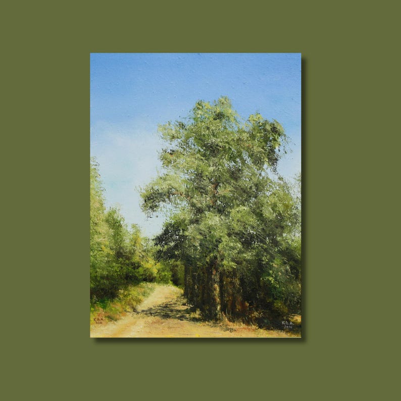 May include: Oil painting of a sunlit dirt path winding through a forest. The artwork features a large tree with lush green foliage on the right, a bright blue sky, and other trees in the background. The painting is framed.