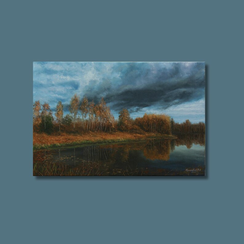 Pu&ograve; includere: Dipinto a olio di un paesaggio con un lago che riflette il cielo e gli alberi. Il cielo &egrave; un misto di nuvole blu e grigio scuro. Alberi con foglie dorate costeggiano la riva. Il dipinto &egrave; incorniciato e montato su sfondo blu.