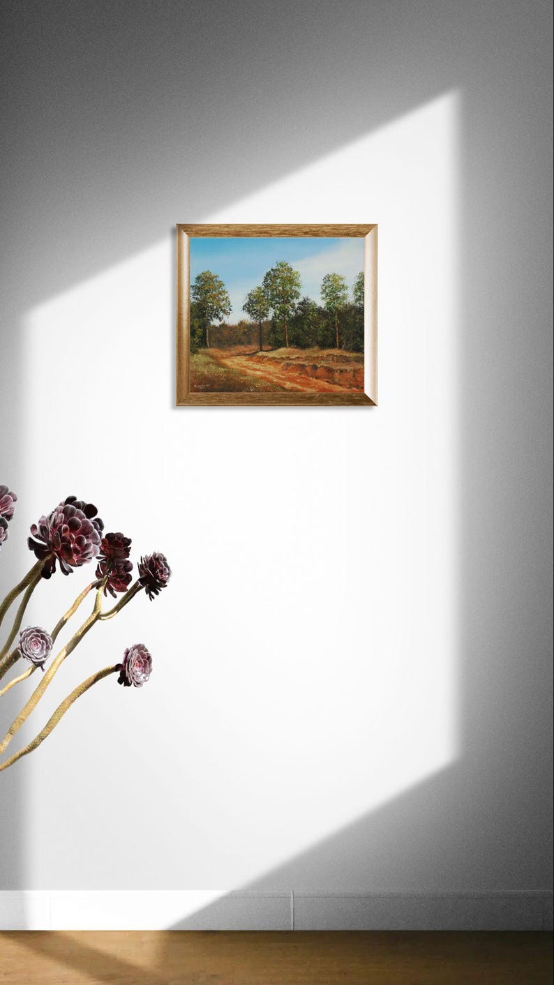 Pu&ograve; includere: Un dipinto di paesaggio incorniciato raffigura un sentiero attraverso una foresta con alberi e cielo blu. L'opera d'arte ha una cornice color oro ed &egrave; esposta su una parete bianca. I colori del dipinto includono verde, marrone e blu.