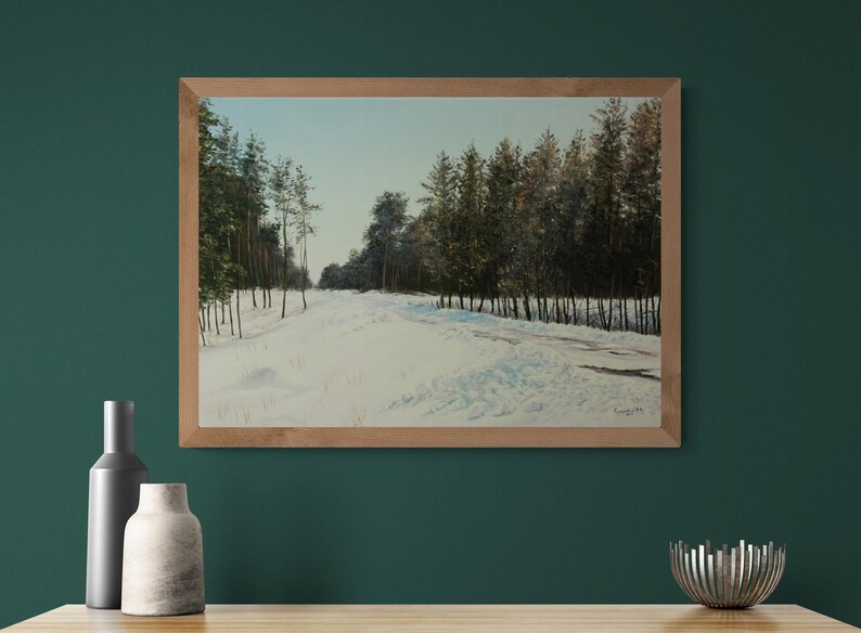 May include: A framed landscape painting depicts a snow-covered path winding through a forest of evergreen trees. The artwork features a palette of white, green, and brown hues, with a light blue sky.