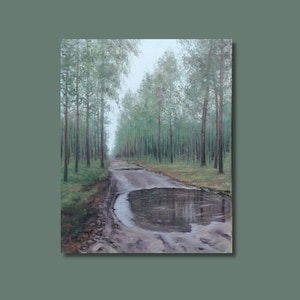 May include: An oil painting of a forest scene. A muddy track leads into the distance, flanked by tall trees with green leaves. A large puddle reflects the sky. The artwork is framed in a muted green.