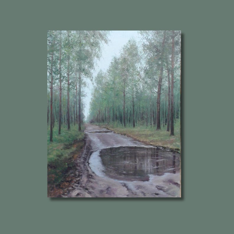 May include: An oil painting of a forest scene. A muddy track leads into the distance, flanked by tall trees with green leaves. A large puddle reflects the sky. The artwork is framed in a muted green.