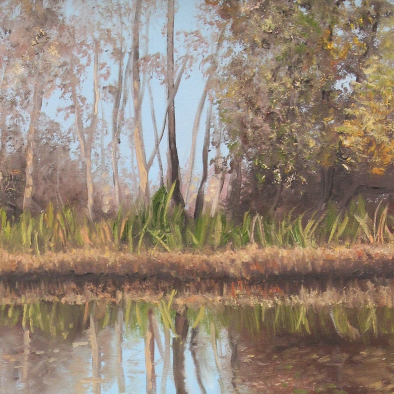 May include: An oil painting depicts a tranquil waterscape with trees and their reflections. Tall, slender trees with light-colored bark stand against a pale blue sky. Green reeds line the water's edge, and the water reflects the trees and sky.