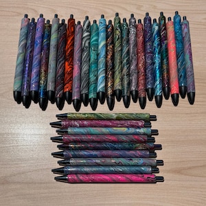 May include: A collection of 27 black and silver pens with marbled designs. The pens are arranged in two rows, with the top row containing 25 pens and the bottom row containing 2 pens.
