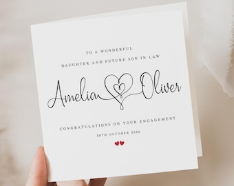 May include: A white engagement card with black script that reads "To a Wonderful Daughter and Future Son in Law" and "Congratulations on Your Engagement." The names "Amelia" and "Oliver" are written in cursive, connected by a heart design. The date "29th October 2024" is also included.