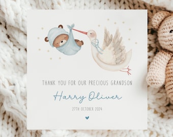 May include: A thank you card with a watercolor illustration of a stork carrying a baby bear in a blue blanket. The card says "Thank you for our precious grandson Harry Oliver 27th October 2024".