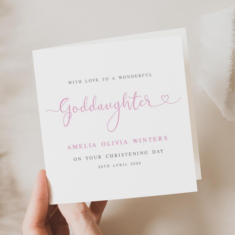 May include: A white card with pink text that reads "With love to a wonderful Goddaughter" and "Amelia Olivia Winters on your christening day 28th April 2024".