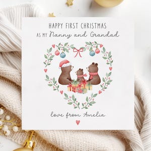 May include: A Christmas card with a watercolor illustration of three bears in a heart-shaped wreath. The card reads "Happy First Christmas as my Nanny and Grandad, love from Amelia".