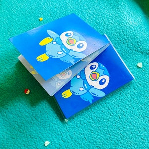May include: Two blue and white illustrated Pokemon character cards featuring Piplup. The cards are stacked on top of each other.