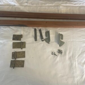 May include: Two wooden bed rails, four brass hinges, two metal brackets, and several screws. These are hardware parts for a bed frame.