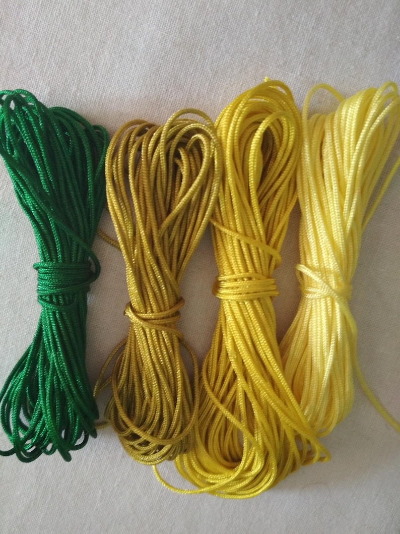 May include: Four spools of cord in shades of green, yellow, and light yellow.