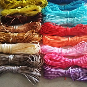 以下が含まれることがあります： 虹色のパターンで配置された、15個のカラフルなワックス加工コットンコードのスプールのコレクション。コードはすべて同じ太さで、クラフトプロジェクトに最適です。