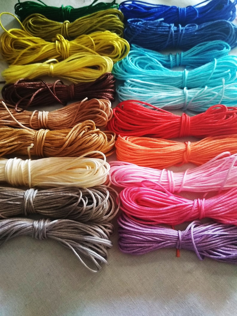 May include: A collection of 15 spools of colorful waxed cotton cord, arranged in a rainbow pattern. The cords are all the same thickness and are perfect for crafting projects.