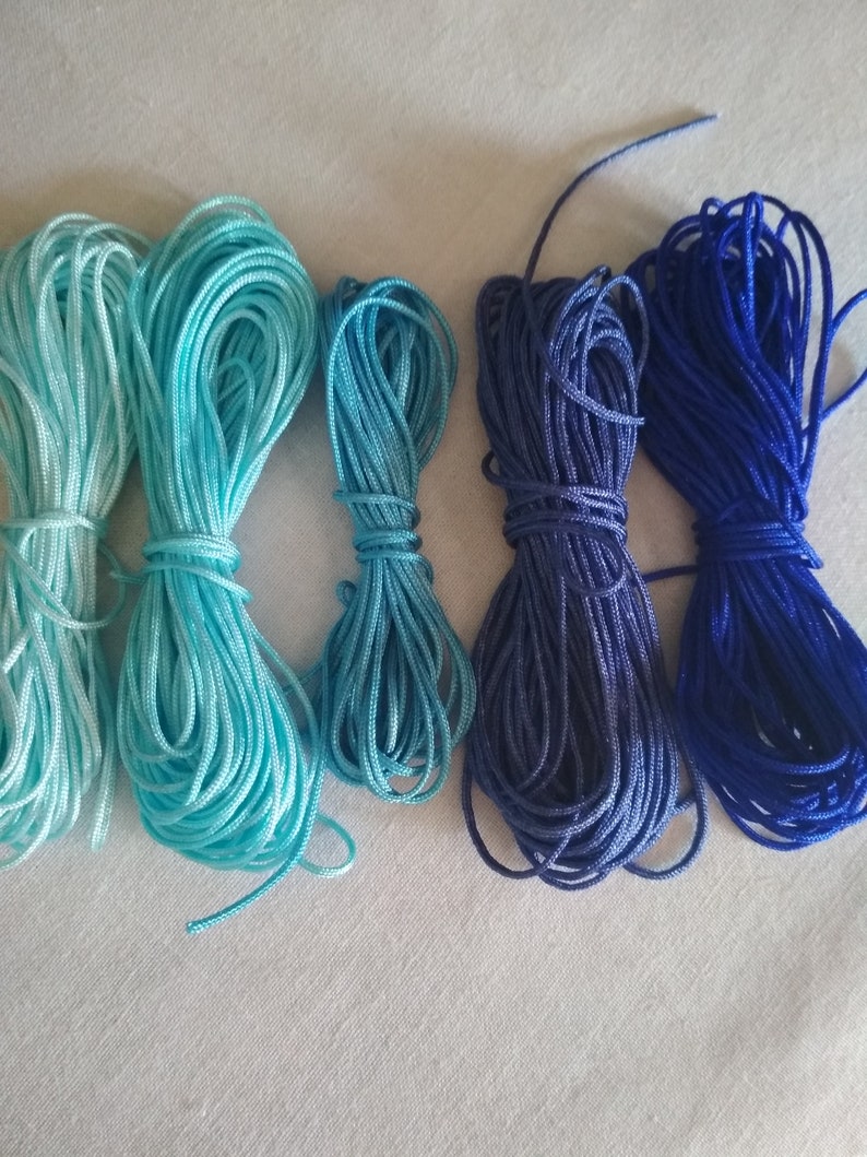 May include: Five spools of embroidery floss in shades of blue, from light blue to dark blue.