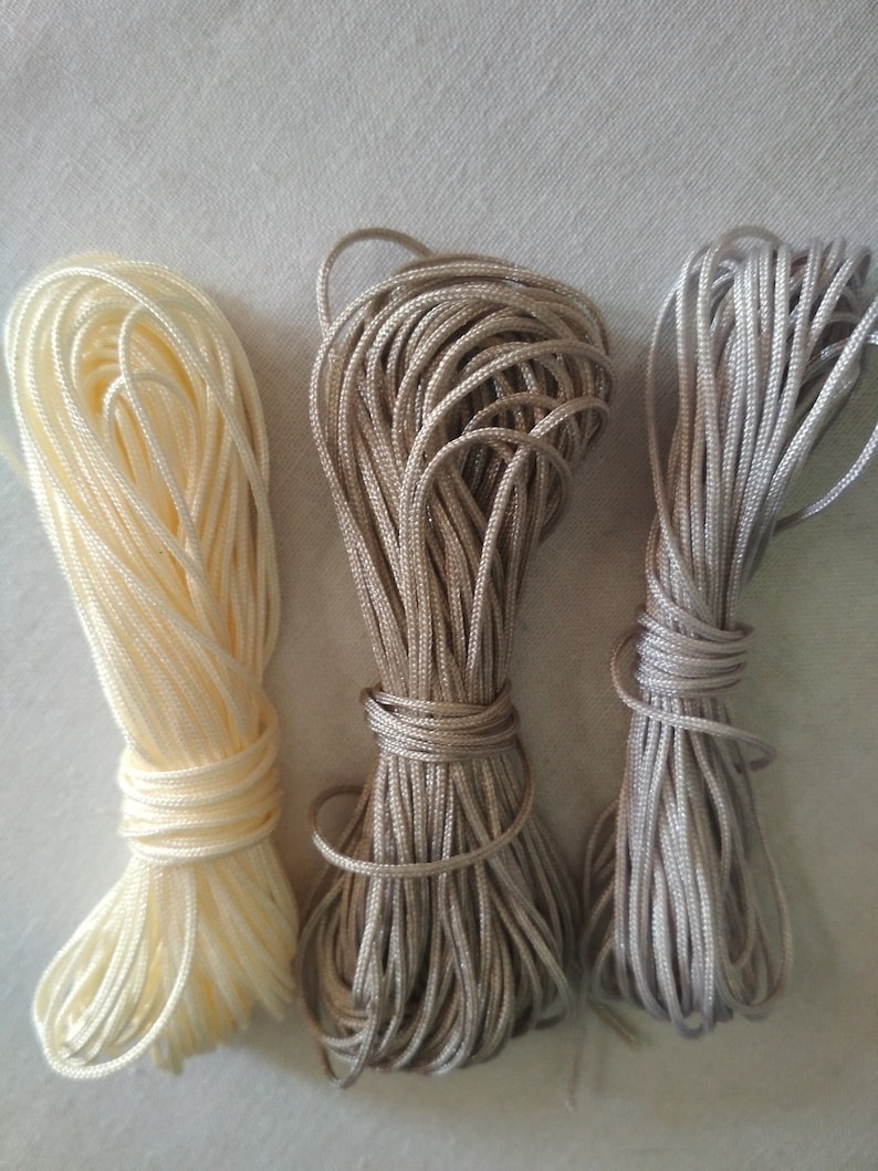 May include: Three spools of cord in different shades of beige. The cord is wound tightly and is ready for crafting projects.