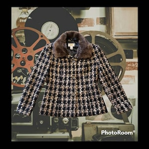 以下が含まれることがあります： 黒と金のツイードジャケットにフェイクファーの襟が付いている。ジャケットはボタン留めで、体にフィットするシルエットです。