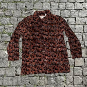 May include: A long-sleeved button-down shirt with a brown and black square pattern. The shirt has a collared neckline and a button closure down the front. The fabric appears to be textured.