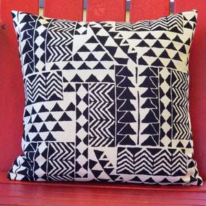 May include: A square throw cushion featuring a high-contrast black and off-white geometric pattern. The design consists of various rectangular and square panels filled with repeating motifs, including solid black triangles and zigzag lines.