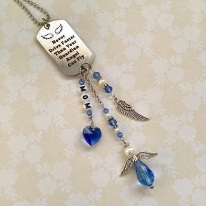 Könnte beinhalten: Silberfarbener Anhänger in Form einer Erkennungsmarke mit dem Text "Never Drive Faster Than Your Guardian Angel Can Fly". Er hat Engelsflügel, blaue Perlen und einen herzförmigen Anhänger. Das Wort "MOM" ist mit weißen Buchstabenperlen geschrieben.