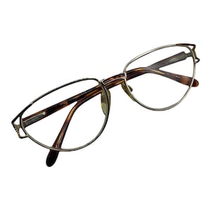 May include: Gold-rimmed eyeglasses with tortoise shell arms. The glasses have a cat-eye shape.