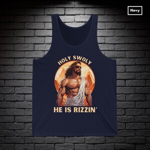 Puede incluir: Una camiseta sin mangas azul marino con un gr&aacute;fico de una figura musculosa de Jes&uacute;s con gafas de sol y el texto "HOLY SWOLY HE IS RIZZIN'" en un c&iacute;rculo.