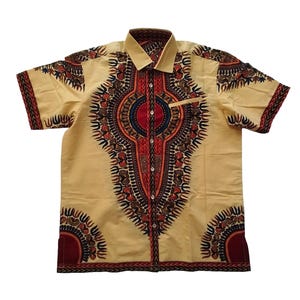 Peut inclure: Une chemise à manches courtes boutonnée de couleur beige clair. La chemise présente un motif symétrique vibrant en rouge, noir et marron, avec une petite poche sur la poitrine. Le col et les poignets ont un design contrasté.
