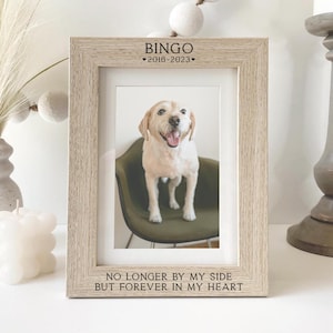 May include: A light wood picture frame with a black and white photo of a dog inside. The frame has the text "Bingo *2018-2023*" and "No longer by my side but forever in my heart" engraved on it.