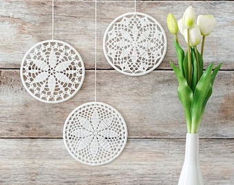 May include: Three white crocheted doilies hanging on a wood wall with a white vase with green tulips.