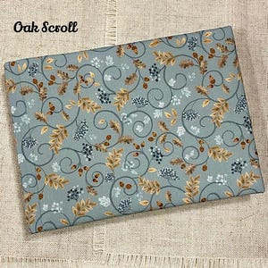 May include: A blue fabric with a repeating pattern of brown leaves, vines, and berries. The fabric has the text "Oak Scroll" printed in the top left corner.
