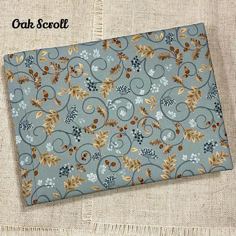 May include: A blue fabric with a repeating pattern of brown leaves, vines, and berries. The fabric has the text "Oak Scroll" printed in the top left corner.