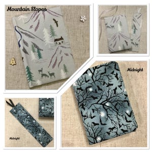May include: Fabric book covers and bookmarks. One cover has a mountain scene with trees, deer, and a cabin. Another features a midnight sky with bats and branches. The text "Mountain Slopes" and "Midnight" are visible.