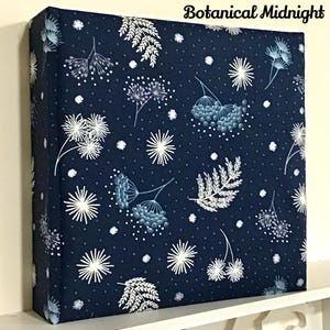 May include: A navy blue fabric square with a white floral pattern and white dots. The fabric has a botanical midnight design.
