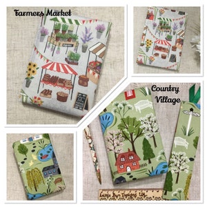 May include: A collection of fabric-covered book covers and a bookmark. Designs include a farmer's market scene with stalls and produce, and a country village with a house and trees. The text "Farmers Market" and "Country Village" are displayed on the covers.