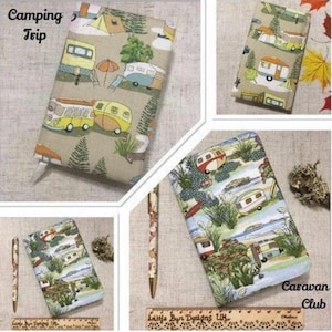 Op de afbeelding: Een stoffen hoes met een Camping Trip-print met gele en blauwe campers, tenten en bomen op een beige achtergrond, samen met een bijpassende pen en een tweede hoes met een Caravan Club-print met campers in een landschap.
