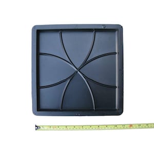 May include: Black plastic mold for creating concrete stepping stones. The mold features a geometric design with six curved sections.