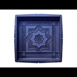 May include: A black plastic mold for making concrete pavers. The mold features a decorative design with a starburst pattern.