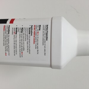 May include: White plastic bottle with a red and black label. The label has instructions for mixing and applying a release agent for concrete forms. The label includes the text "G-1 Release" and "DO NOT FOAM the solution."