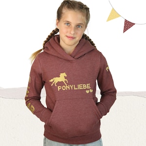 Puede incluir: Sudadera con capucha color burdeos con un caballo dorado y el texto "PONYLIEBE" impreso en la parte delantera. La sudadera tiene un caballo dorado en la manga.