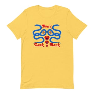 May include: Yellow t-shirt with a graphic design featuring two blue snakes, red hearts, and the text "Don't Look Back" in red. The snakes have yellow eyes and are intertwined.
