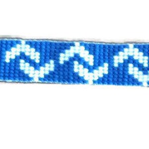 May include: A blue and white patterned keychain with a silver key ring and a feather charm. The keychain features a woven design with a repeating wave pattern in white against a blue background. The ends are finished with white fabric.