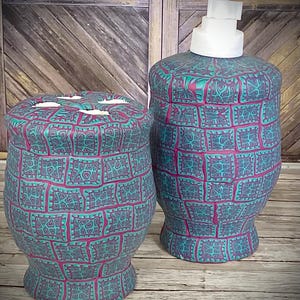 Peut inclure: Un ensemble de salle de bain turquoise et magenta comprenant un distributeur de savon avec une pompe blanche et un porte-brosse à dents assorti. L'ensemble présente un motif texturé. Le fond est une surface en bois.
